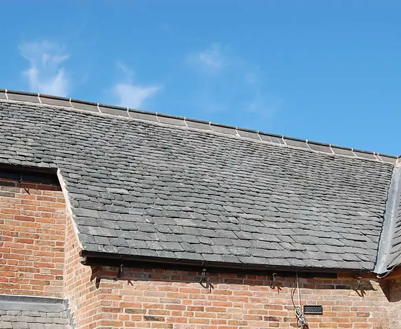 Grey slate roof and brick courtyard walls under a blue sky